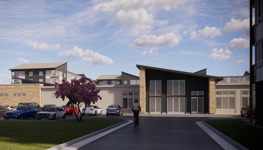 Modern multifamily development with parking, landscaping, and contemporary architecture under blue sky.