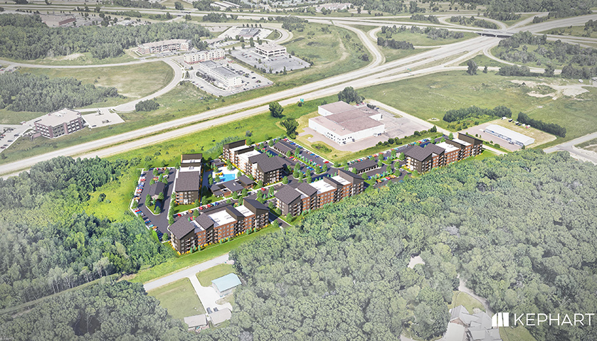 Aerial view of multifamily investment properties with residential buildings, amenities, and surrounding woodlands near highway infrastructure.
