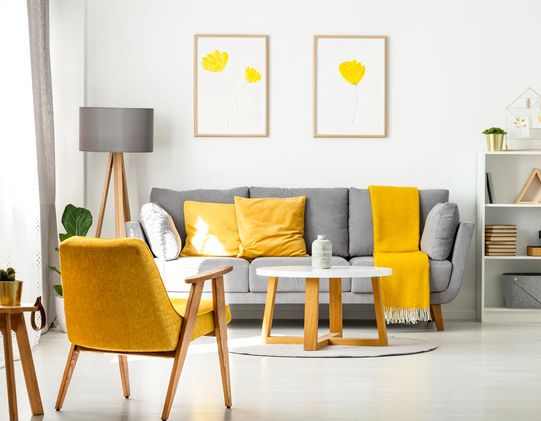 Bright modern living room with a gray sofa accented by yellow cushions and a yellow throw, and yellow chairs nearby.